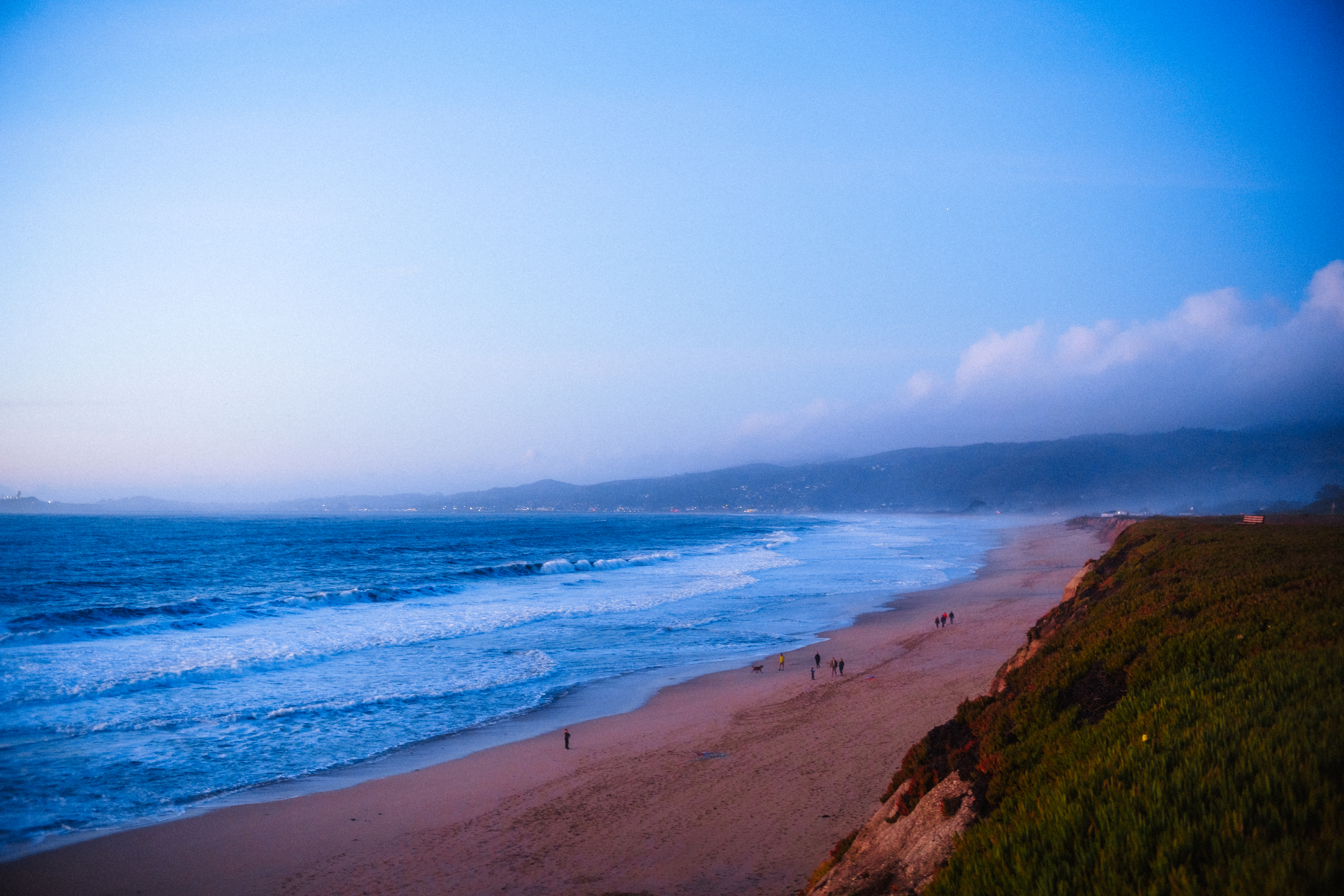 Waves breaking along a sandy ocean beach at dusk